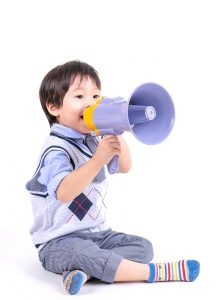 Portrait asian little boy sitting and smiling with happiness and joyful to playing with megaphone on white background, copy space